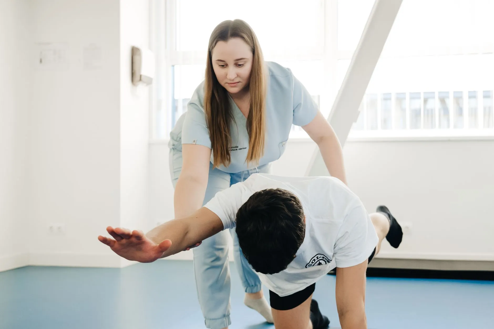 Fisioterapeuta corrige a posição de um paciente durante exercício em quatro apoios na sessão de fisioterapia
